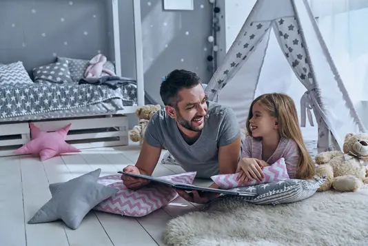 Haus-Vater-Tochter-Wohnen-Serie-4-5 Vater liest seiner Tochter ein Buch vor.