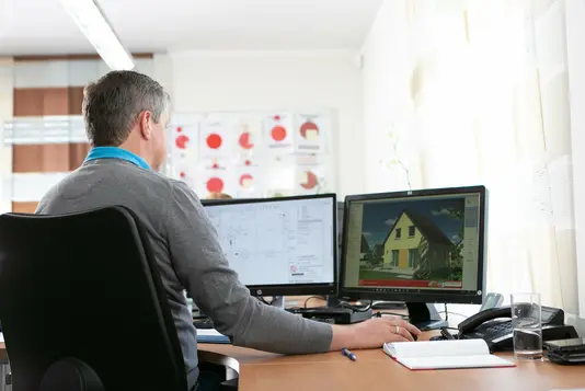 Baugenehmigung-Bauantrag-Ratgeber-Town-Country-Haus-07 Mann vor zwei Computerbildschirmen